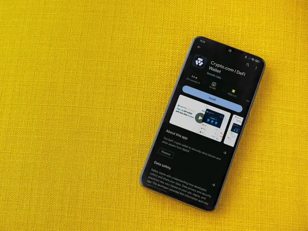 Lod, Israel - 16 Temmuz 2023: Crypto.com uygulama oyun mağazası sayfası sarı kumaş arka planda akıllı telefon. Üst görünüm düzlüğü kopyalama alanı ile yatıyordu.