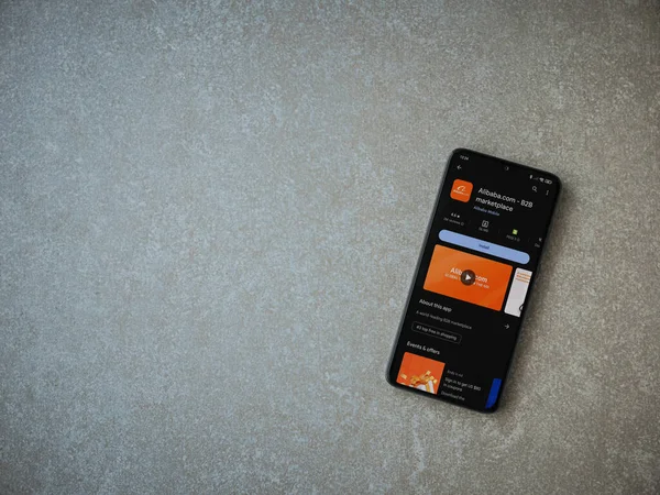 Lod, Israel - 16 Temmuz 2023: Alibaba.com uygulama oyun mağazası sayfası seramik taş zemin üzerinde akıllı telefon. Üst görünüm düzlüğü kopyalama alanı ile yatıyordu.
