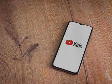 Lod, Israel - 16 Temmuz 2023: YouTube Kids uygulama ekranı ahşap arka planda akıllı telefondan çalıştırıldı. Üst görünüm düzlüğü kopyalama alanı ile yatıyordu.