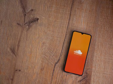 Lod, Israel - 16 Temmuz 2023: SoundCloud uygulama ekranı ahşap zemin üzerinde akıllı telefon. Üst görünüm düzlüğü kopyalama alanı ile yatıyordu.