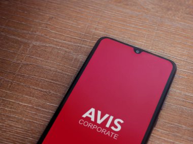 Lod, Israel - 16 Temmuz 2023: Avis Corporate uygulaması ahşap zemin üzerinde akıllı telefon fırlatma ekranı. Üst görünüm düzlüğü kopyalama alanı ile yatıyordu.