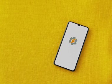 Lod, Israel - 16 Temmuz 2023: Sarı kumaş arka planda akıllı telefondan Tasker uygulaması fırlatma ekranı. Üst görünüm düzlüğü kopyalama alanı ile yatıyordu.