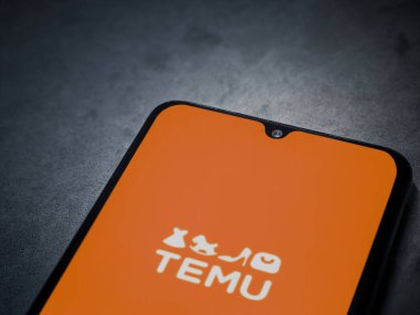 Lod, Israel - 16 Temmuz 2023: Koyu mermer taşlı arka planda akıllı telefondan Temu uygulaması fırlatma ekranı. Üst görünüm düzlüğü kopyalama alanı ile yatıyordu.