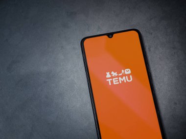 Lod, Israel - 16 Temmuz 2023: Koyu mermer taşlı arka planda akıllı telefondan Temu uygulaması fırlatma ekranı. Üst görünüm düzlüğü kopyalama alanı ile yatıyordu.