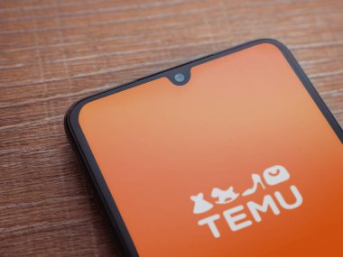 Lod, Israel - 16 Temmuz 2023: Ahşap arka planda akıllı telefondan Temu uygulama başlatma ekranı. Üst görünüm düzlüğü kopyalama alanı ile yatıyordu.