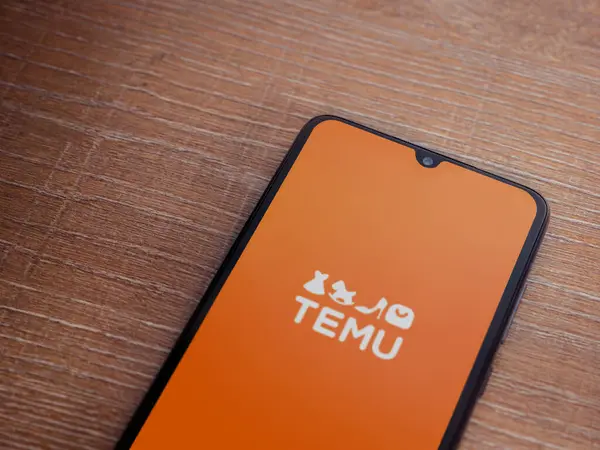 stock image Lod, Israel - July 16,2023: Temu app launch screen on smartphone on wooden background. Top view flat lay with copy space.