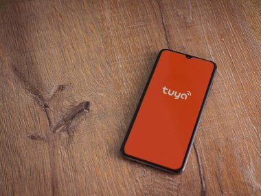 Lod, Israel - 16 Temmuz 2023: Tuya Smart uygulama ekranı ahşap arka planda akıllı telefon. Üst görünüm düzlüğü kopyalama alanı ile yatıyordu.