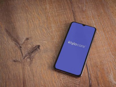 Lod, Israel - 16 Temmuz 2023: TytoCare uygulaması ahşap arka planda akıllı telefondan kalkış ekranı. Üst görünüm düzlüğü kopyalama alanı ile yatıyordu.