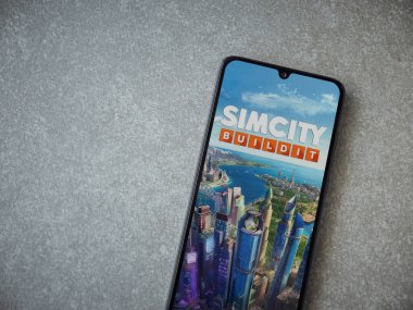 Lod, Israel - 16 Temmuz 2023: SimCity BuildIt uygulaması seramik taş zemin üzerinde akıllı telefon fırlatma ekranı. Üst görünüm düzlüğü kopyalama alanı ile yatıyordu.