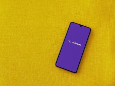 Lod, Israel - 16 Temmuz 2023: WorldRemit uygulaması sarı kumaş arka planda akıllı telefondan çalıştırma ekranı. Üst görünüm düzlüğü kopyalama alanı ile yatıyordu.