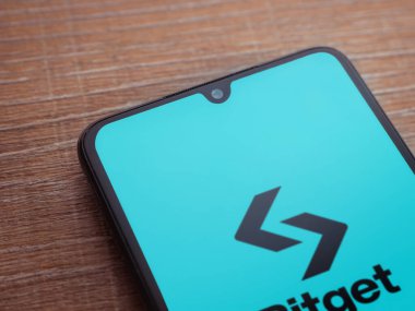 Lod, Israel - 16 Temmuz 2023: Bitget uygulaması ahşap arka planda akıllı telefondan çalıştırma ekranı. Üst görünüm düzlüğü kopyalama alanı ile yatıyordu.