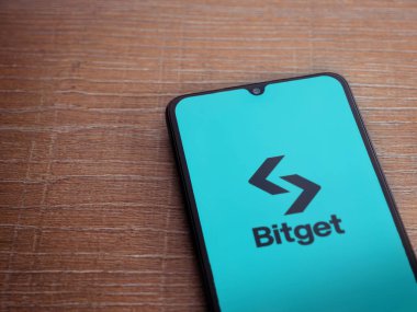 Lod, Israel - 16 Temmuz 2023: Bitget uygulaması ahşap arka planda akıllı telefondan çalıştırma ekranı. Üst görünüm düzlüğü kopyalama alanı ile yatıyordu.