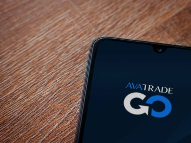 Lod, Israel - 16 Temmuz 2023: Ahşap arka planda akıllı telefondan Avatrade uygulaması fırlatma ekranı. Üst görünüm düzlüğü kopyalama alanı ile yatıyordu.