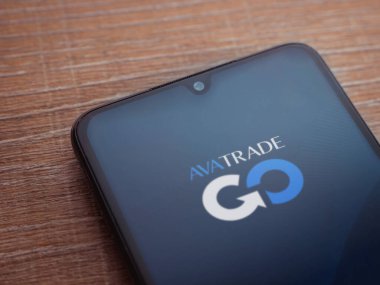 Lod, Israel - 16 Temmuz 2023: Ahşap arka planda akıllı telefondan Avatrade uygulaması fırlatma ekranı. Üst görünüm düzlüğü kopyalama alanı ile yatıyordu.