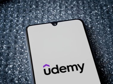 Lod, Israel - 16 Temmuz 2023: Metalik arka planda siyah bir cep telefonunun ekranında Udemy uygulamasını çalıştırma ekranı. Üst görünüm yatağını kapat.