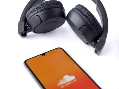 Lod, Israel - 16 Temmuz 2023: SoundCloud uygulama ekranlı akıllı telefon ve beyaz arka planda kablosuz kulaklıklar. Üst görünüm düzlüğü kopyalama alanı ile yatıyordu.