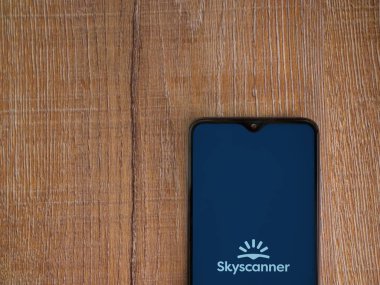 Lod, Israel - 16 Temmuz 2023: Skyscanner uygulaması ahşap arka planda akıllı telefondan çalıştırma ekranı. Üst görünüm düzlüğü kopyalama alanı ile yatıyordu.