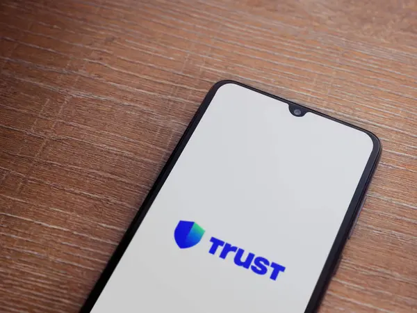 stock image Lod, Israel - July 16,2023: Trust Wallet app launch screen on smartphone on wooden background. Top view flat lay with copy space.