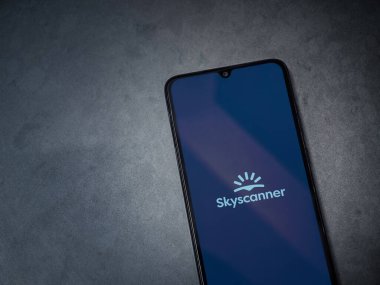 Lod, Israel - 16 Temmuz 2023: Skyscanner uygulaması koyu mermer taşlı arka planda akıllı telefondan kalkış ekranı. Üst görünüm düzlüğü kopyalama alanı ile yatıyordu.
