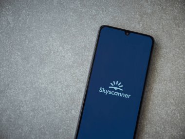 Lod, Israel - 16 Temmuz 2023: Skyscanner uygulaması seramik taş zemin üzerinde akıllı telefon fırlatma ekranı. Üst görünüm düzlüğü kopyalama alanı ile yatıyordu.
