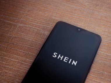 Lod, Israel - 16 Temmuz 2023: Shein uygulaması ahşap arka planda akıllı telefondan çalıştırma ekranı. Üst görünüm düzlüğü kopyalama alanı ile yatıyordu.
