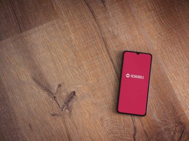 Lod, Israel - 16 Temmuz 2023: Ahşap arka planda akıllı telefondan kırmızı baloncuklu uygulama fırlatma ekranı. Üst görünüm düzlüğü kopyalama alanı ile yatıyordu.