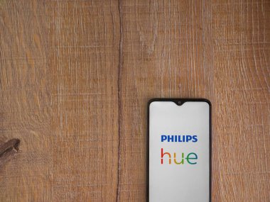 Lod, Israel - 16 Temmuz 2023: Philips Hue uygulaması ahşap arka planda akıllı telefondan kalkış ekranı. Üst görünüm düzlüğü kopyalama alanı ile yatıyordu.