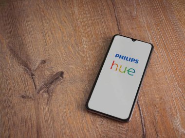 Lod, Israel - 16 Temmuz 2023: Philips Hue uygulaması ahşap arka planda akıllı telefondan kalkış ekranı. Üst görünüm düzlüğü kopyalama alanı ile yatıyordu.