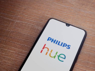 Lod, Israel - 16 Temmuz 2023: Philips Hue uygulaması ahşap arka planda akıllı telefondan kalkış ekranı. Üst görünüm düzlüğü kopyalama alanı ile yatıyordu.