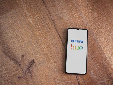 Lod, Israel - 16 Temmuz 2023: Philips Hue uygulaması ahşap arka planda akıllı telefondan kalkış ekranı. Üst görünüm düzlüğü kopyalama alanı ile yatıyordu.