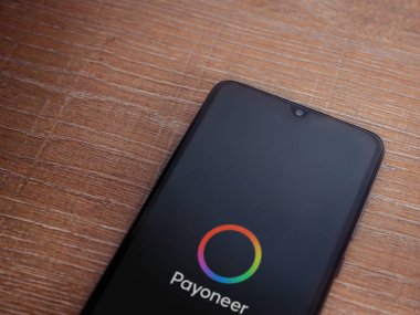 Lod, Israel - 16 Temmuz 2023: Ahşap zemin üzerinde Payoneer uygulama fırlatma ekranı. Üst görünüm düzlüğü kopyalama alanı ile yatıyordu.