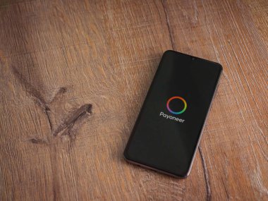Lod, Israel - 16 Temmuz 2023: Ahşap zemin üzerinde Payoneer uygulama fırlatma ekranı. Üst görünüm düzlüğü kopyalama alanı ile yatıyordu.