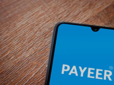 Lod, Israel - 16 Temmuz 2023: PaYEER uygulama ekranı ahşap arka planda akıllı telefon. Üst görünüm düzlüğü kopyalama alanı ile yatıyordu.