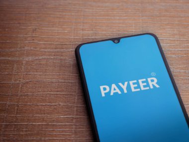 Lod, Israel - 16 Temmuz 2023: PaYEER uygulama ekranı ahşap arka planda akıllı telefon. Üst görünüm düzlüğü kopyalama alanı ile yatıyordu.