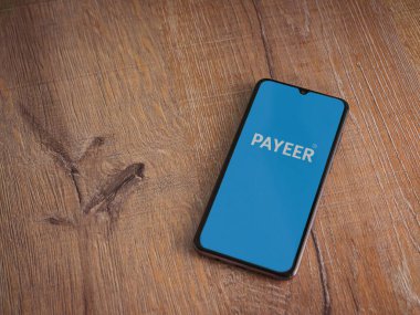 Lod, Israel - 16 Temmuz 2023: PaYEER uygulama ekranı ahşap arka planda akıllı telefon. Üst görünüm düzlüğü kopyalama alanı ile yatıyordu.