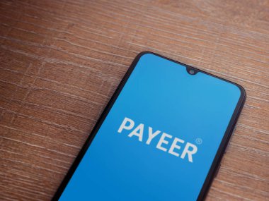 Lod, Israel - 16 Temmuz 2023: PaYEER uygulama ekranı ahşap arka planda akıllı telefon. Üst görünüm düzlüğü kopyalama alanı ile yatıyordu.