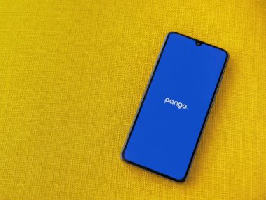 Lod, Israel - 16 Temmuz 2023: Pango uygulama ekranı sarı kumaş arka planda akıllı telefon. Üst görünüm düzlüğü kopyalama alanı ile yatıyordu.
