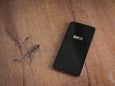 Lod, Israel - 16 Temmuz 2023: OKX uygulama ekranı ahşap arka planda akıllı telefon. Üst görünüm düzlüğü kopyalama alanı ile yatıyordu.