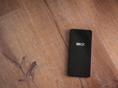 Lod, Israel - 16 Temmuz 2023: OKX uygulama ekranı ahşap arka planda akıllı telefon. Üst görünüm düzlüğü kopyalama alanı ile yatıyordu.