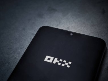 Lod, Israel - 16 Temmuz 2023: OKX uygulaması koyu mermer taşlı arka planda akıllı telefondan kalkış ekranı. Üst görünüm düzlüğü kopyalama alanı ile yatıyordu.