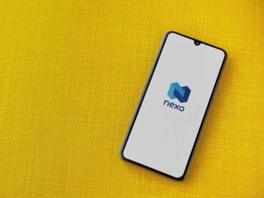 Lod, Israel - 16 Temmuz 2023: Sarı kumaş arka planda akıllı telefondan Nexo uygulaması fırlatma ekranı. Üst görünüm düzlüğü kopyalama alanı ile yatıyordu.
