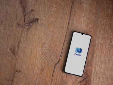 Lod, Israel - 16 Temmuz 2023: Ahşap arka planda akıllı telefondan Nexo uygulama fırlatma ekranı. Üst görünüm düzlüğü kopyalama alanı ile yatıyordu.