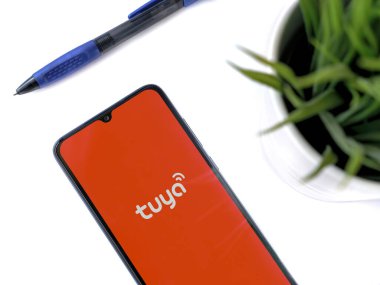 Lod, Israel - 16 Temmuz 2023: Beyaz arka planda Tuya Smart uygulamalı akıllı telefonlu modern çalışma alanı. Üst görünüm yatağını kapat.