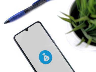 Lod, Israel - 16 Temmuz 2023: Beyaz arka planda Spender uygulamalı akıllı telefonlu modern çalışma alanı. Üst görünüm yatağını kapat.