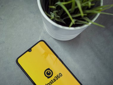 Lod, Israel - 16 Temmuz 2023: Mermer arka planda Insta360 uygulamalı akıllı telefonlu modern çalışma alanı. Üst görünüm yatağını kapat.