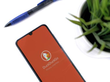 Lod, Israel - 16 Temmuz 2023: DuckGo Özel Tarayıcı uygulamalı akıllı telefonlu modern çalışma alanı beyaz arka planda. Üst görünüm yatağını kapat.