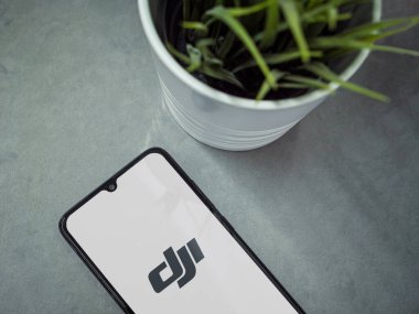 Lod, Israel - 16 Temmuz 2023: Mermer arka planda DJI Store uygulamalı akıllı telefonlu modern çalışma alanı. Üst görünüm yatağını kapat.