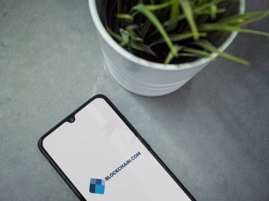 Lod, Israel - 16 Temmuz 2023: Mermer zemin üzerinde Blockchain.com uygulaması olan akıllı telefonlu modern çalışma alanı. Üst görünüm yatağını kapat.