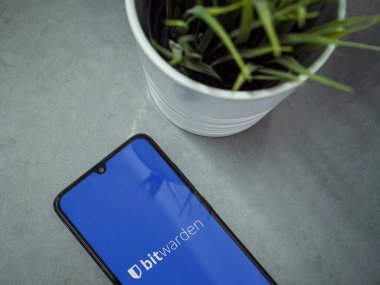 Lod, Israel - 16 Temmuz 2023: Bitwarden Şifre Yöneticisi uygulama ekranlı akıllı telefonlu modern çalışma alanı mermer arka planda. Üst görünüm yatağını kapat.