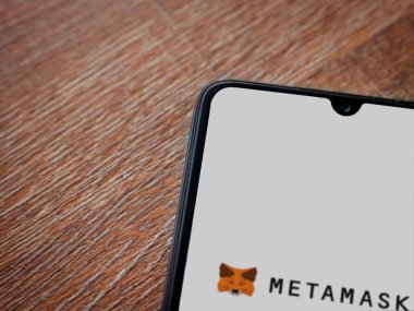 Lod, Israel - 16 Temmuz 2023: MetaMaske uygulaması ahşap arka planda akıllı telefondan çalıştırma ekranı. Üst görünüm düzlüğü kopyalama alanı ile yatıyordu.